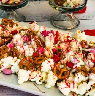 Valentine’s Day Snack Popcorn on a white plate with glasses in the back