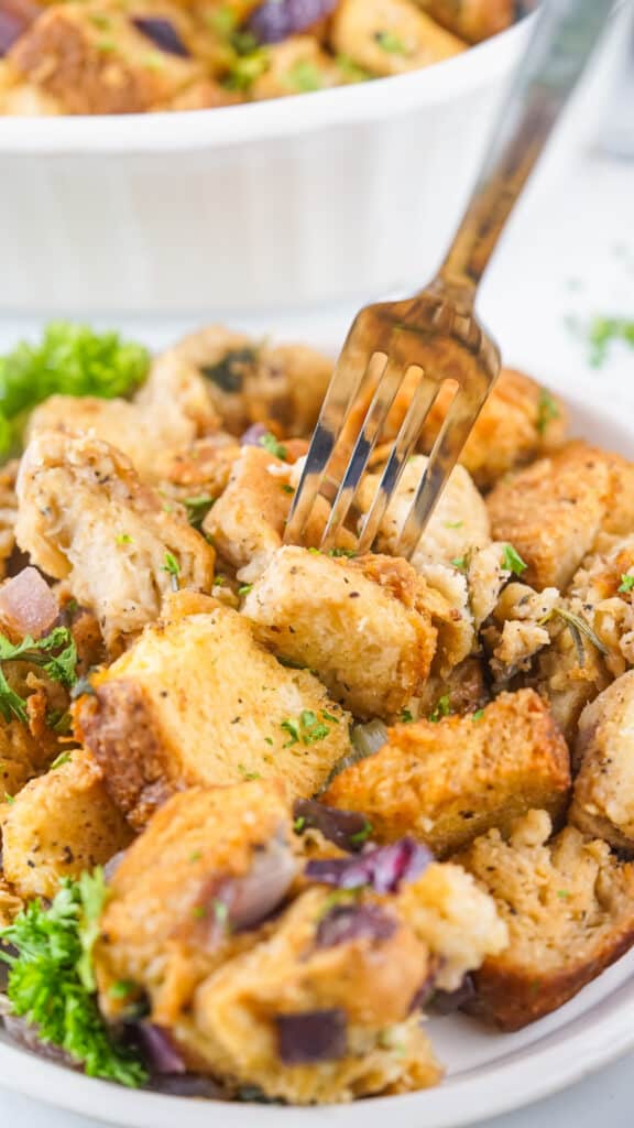 A close-up of a fork picking up a piece of savory Traeger smoked stuffing seasoned with herbs.