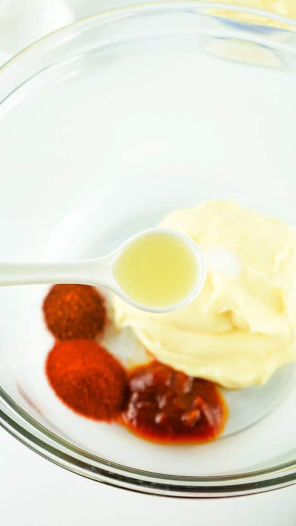 A bowl containing homemade chipotle mayo, ketchup, olive oil, and spices prepped for mixing.