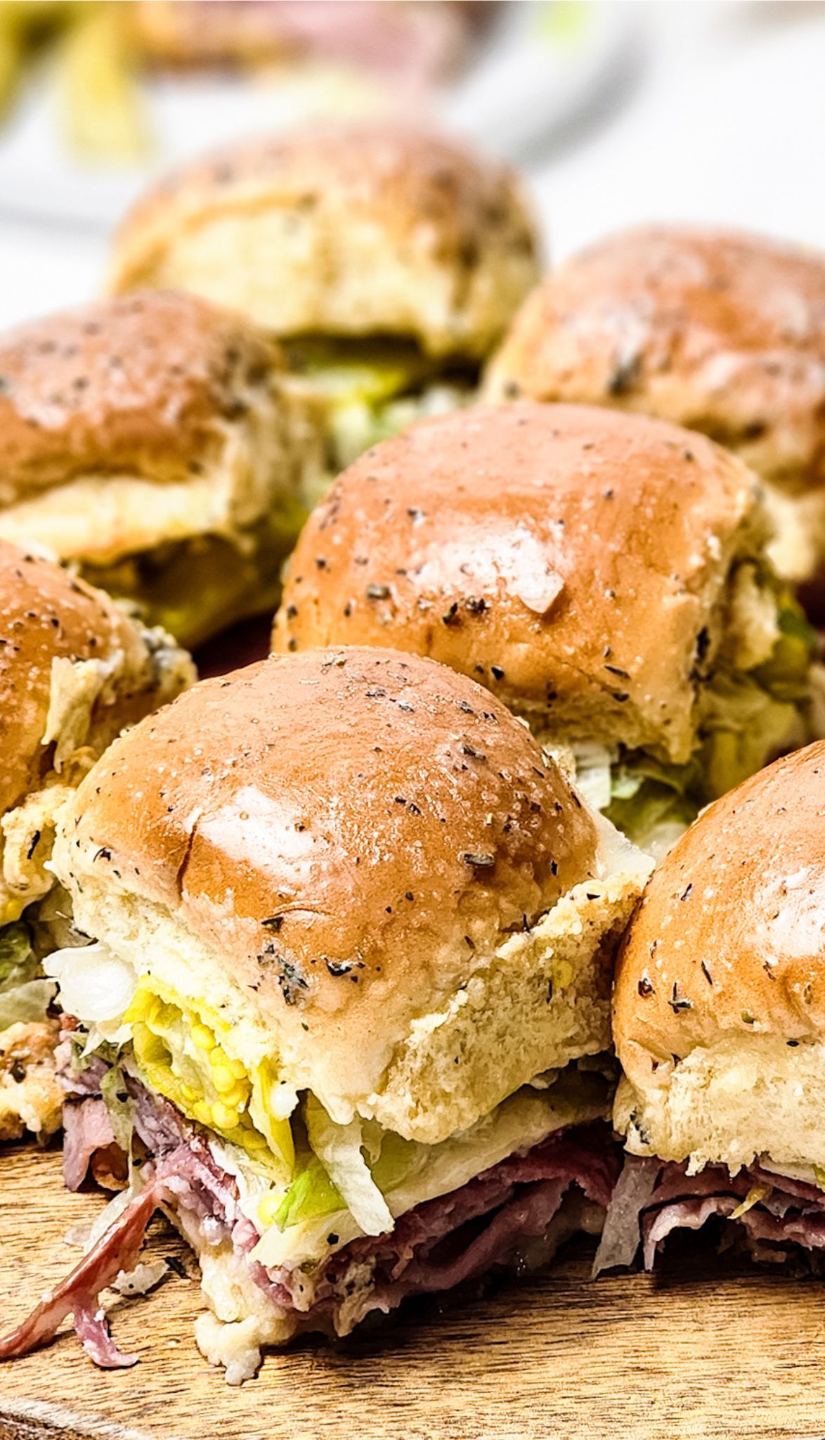 Close-up of several Italian sliders on a wooden board.