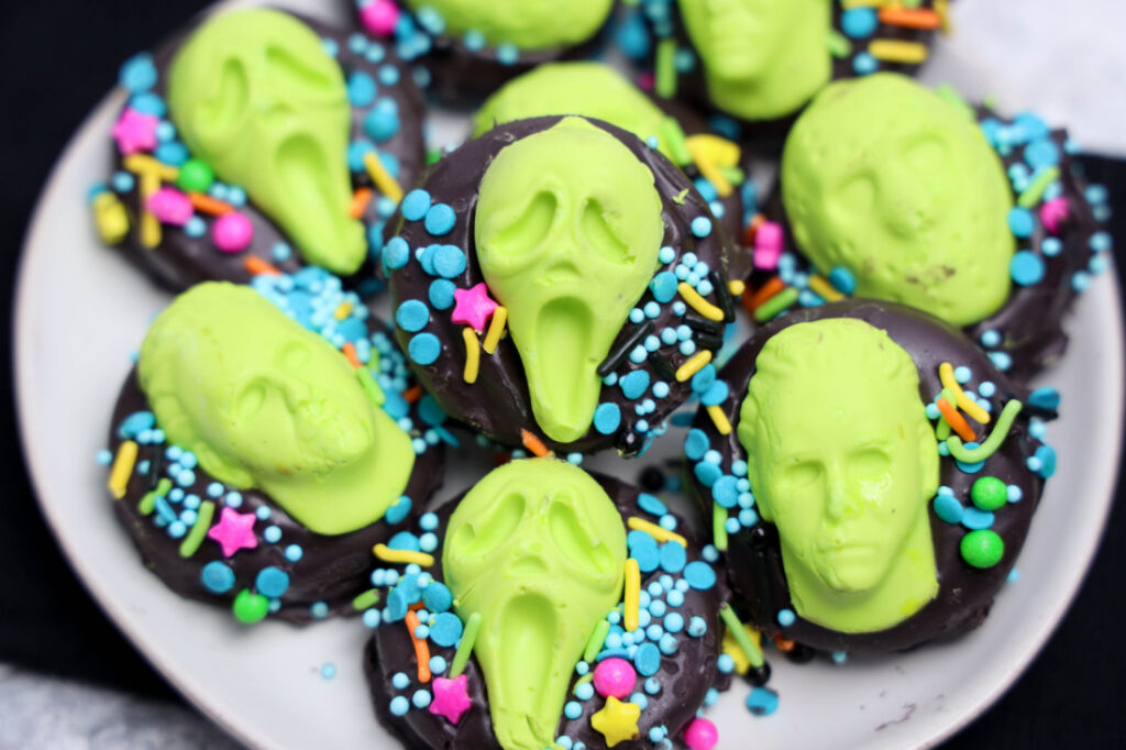 Summerween Slasher Oreos 10 A plate of Summerween Slasher Oreos topped with neon green faces and decorated with colorful sprinkles.