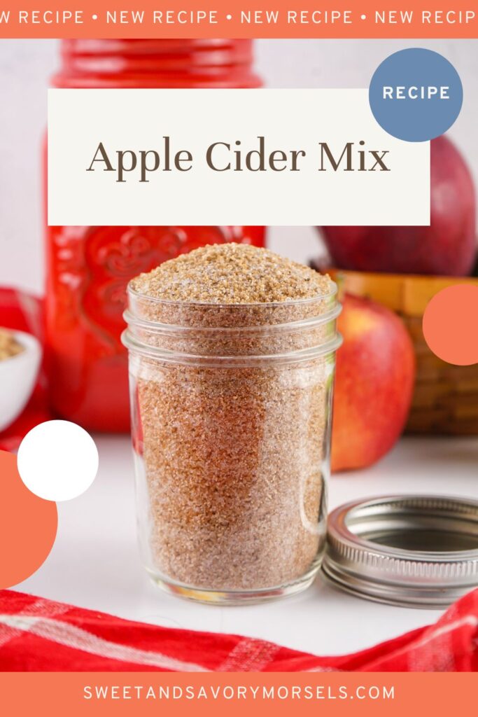 A glass jar of Apple Cider Mix sits on a table with fresh red apples, a red jar, and a red checkered cloth in the background.